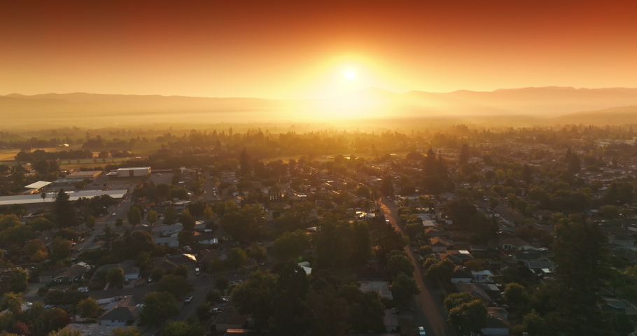 Amazing orange bright sky over Napa, California, USA. Drone flying over the cozy houses in the rays of setting sun.