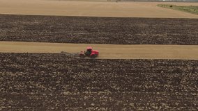 agriculture. tractor plows the soil. industry business agriculture concept. aerial drone video. red tractor machine plows the land with a large plow farm turns over pieces of dirt