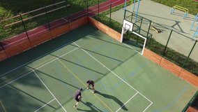 Two friends play one-on-one basketball on an artificial court in summer weather. Active leisure time. Relieve stress by playing. 4k video