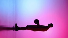 Professional basketball player training with basketball ball at studio over gradient blue pink neon background. Sport, action, motion, skill concept. Slow motion effect