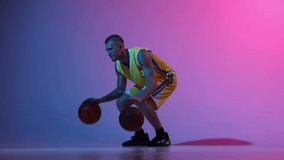 Winner emotions. One young male basketball player dribbling two basketball balls at once over gradient blue pink neon background. Sport, action, motion, skill concept. Slow motion effect