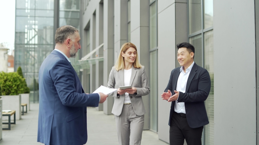meeting of business team partners outside. Negotiations of a group of business people shaking hands, getting to know each other, discussing a project near an office building diverse employees in suit Royalty-Free Stock Footage #1094115361