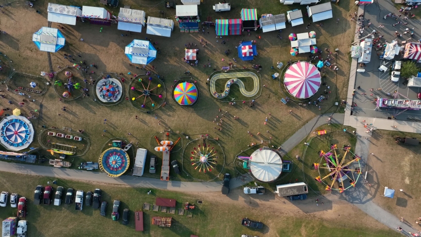 Colorful carnival rides. Top down aerial of fair festival at fairgrounds in USA. Royalty-Free Stock Footage #1094120459