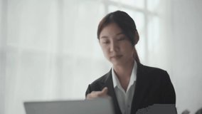 Confident, pretty, smart asian business woman, financial coach or top manager sitting at table, talks with coworkers or clients by video link, showing graphs, conducts consultation, smiles friendly