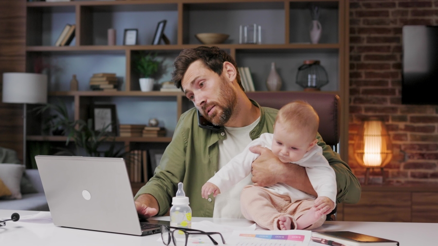 Father on maternity leave, holding an online conference, home office meeting with a small child in his arms. Dad with a child. Combines childcare and work.Holiday to care for the baby.Paternity Leave Royalty-Free Stock Footage #1094126783