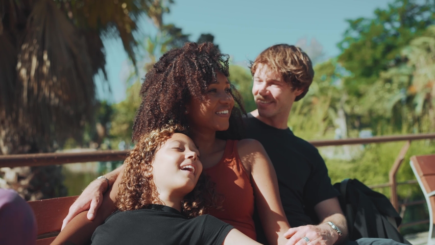 Smiling family talking while sitting on the bench in the park at summer
