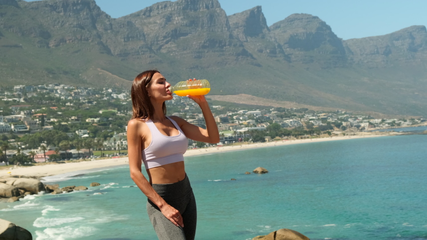 Unrecognizable woman drinking orange or carrot fresh vitamin juice. sporty young woman drinking detox juice while doing exercise. athletic woman drinking orange juice in park after workout