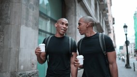 Two smiling bald African brothers talking and walking with cups of coffee on the street outdoors - Powered by Shutterstock - Get 15% off with code: PIKWIZARD15