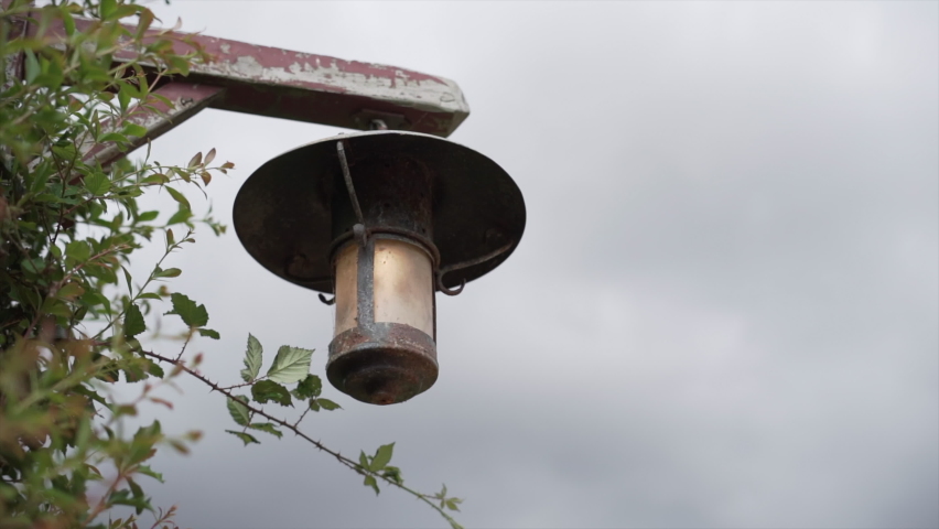 Antique streetlight hanging in Lord of the Rings set, cloudy sky in the background 