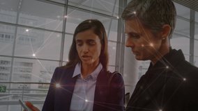 Animation of network of connections over two diverse businesswomen discussing at office. Global networking and business technology concept - Powered by Shutterstock - Get 15% off with code: PIKWIZARD15