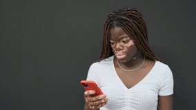 African American woman with vitiligo smiling while using a mobile phone.