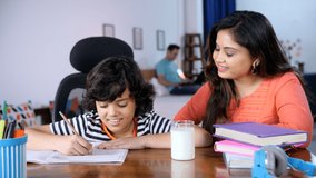 A cheerful Indian housewife offering milk to his son - caring mother, healthy drink, calcium food, kids health kids nutrition . A young boy studying for exams - mother offering milk, happy family, ... - Powered by Shutterstock - Get 15% off with code: PIKWIZARD15