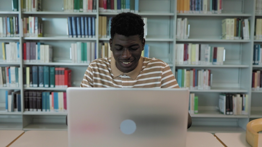 Young African student using laptop in library - School education concept