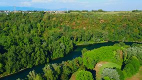 Trezzo sul Adda, Italy. Aerial view of a mountain freshwater river with a low water level surrounded by green trees. White swans on the river. Forest. Wildlife. Green Planet. Ecology. drone video
