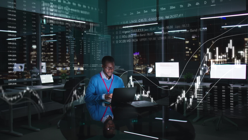 African-American trader work on computer in night office with stock market holograms around. Trader buy and sell shares on laptop Royalty-Free Stock Footage #1094161743