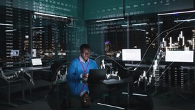 African-American trader work on computer in night office with stock market holograms around. Trader buy and sell shares on laptop