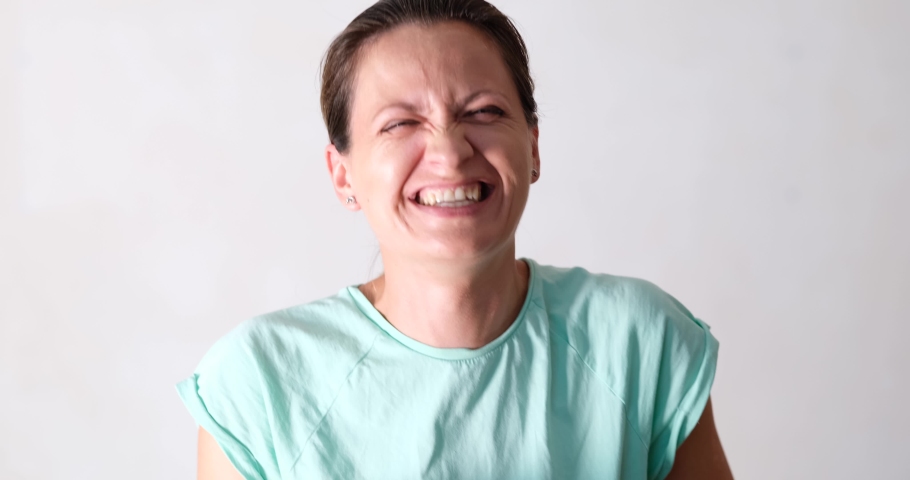 A woman in a tank top laughs, close-up
