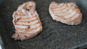Two slices of tuna fish steaks is fried in a ribbed grill pan with hot steam. Cooking fried fillet fish in a hot pan without adding oil - diet mediterranean food