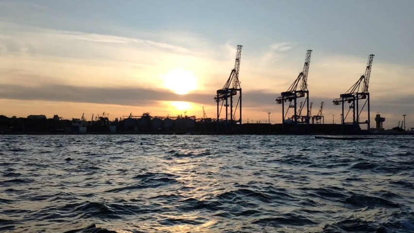 Sunset view of the sea cargo port and container terminal of Odessa. Ships loading by cranes in the evening against the backdrop of the setting sun. View from sea on boat Royalty-Free Stock Footage #1094164361