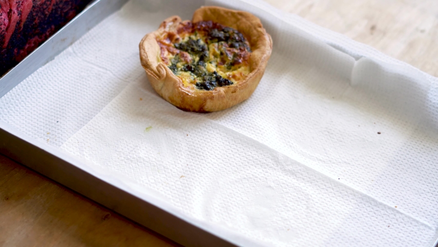 Close up, male hand puts some quiches on a tray.