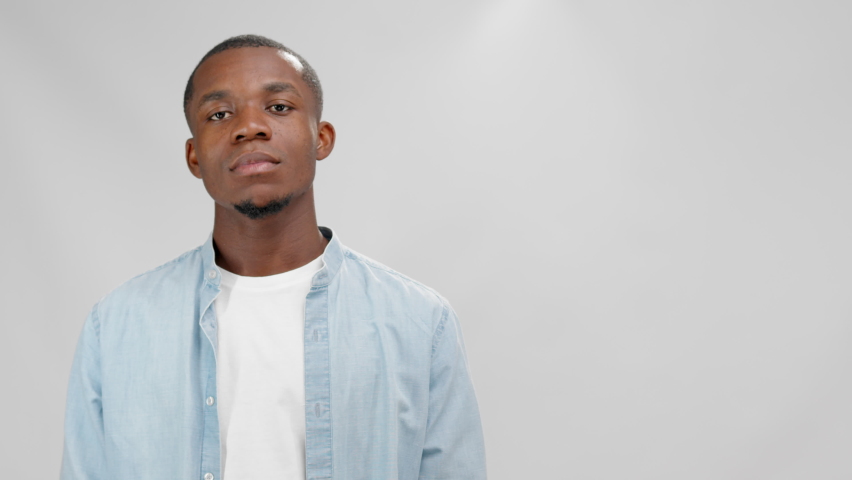 Serious young african american man holding red banner with inscription sale.