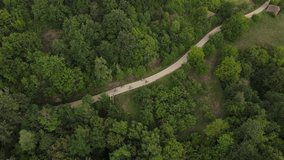 Drone video from above follow group of people riding electric bikes e-bike bicycles on the asphalt in rural countryside road in summer day having fun leisure activity recreation concept 