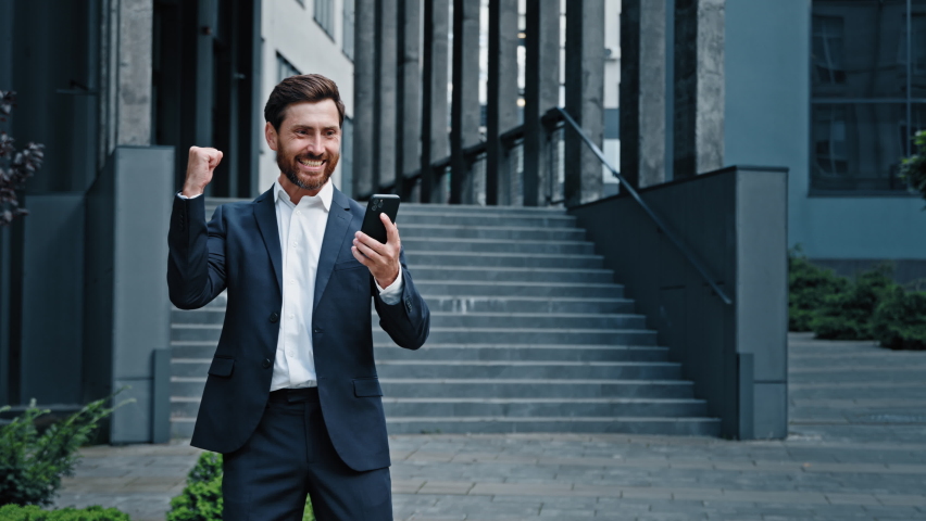 Excited enthusiastic young man standing outdoors reading email on phone with good news receiving great offer job promotion winning lottery receives cash prize celebrating victory rejoicing in success | Shutterstock HD Video #1094171097