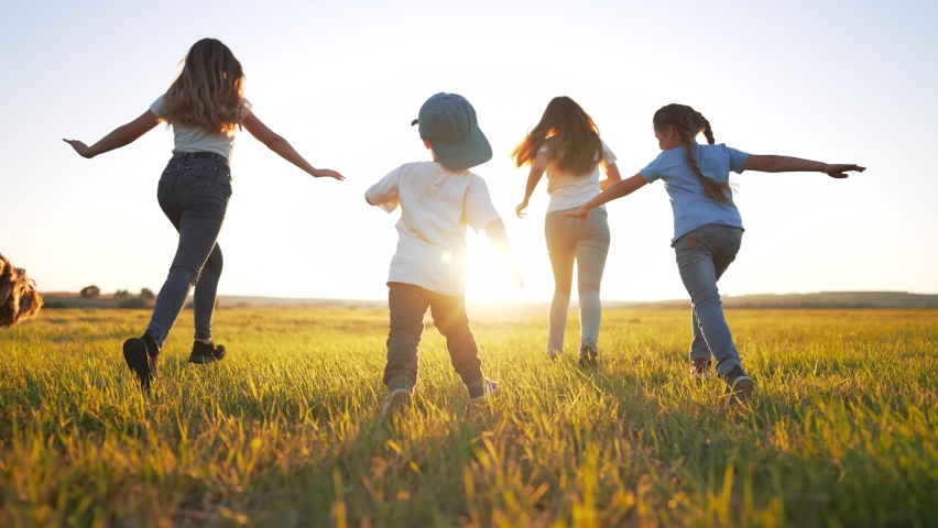 Happy family.Group of cheerful children with dog run through green grass.Family walk with dog at sunset in park.Smile of active children.Children run across field together with dog. Freedom of life Royalty-Free Stock Footage #1094180149