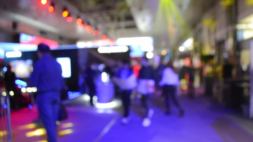 Blurred background large screen stage many people multicolored floodlight performens inside space shopping center or mall, exhibition, exposition
