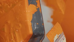 Vertical video: Mom and kid painting walls with orange color and paintbrush, using renovating diy tools at home. People working on redecoration improvement with paint and equipment. Close up.