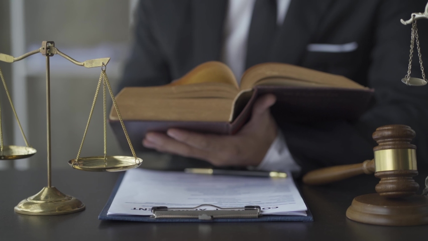 Lawyers read law books in the office. The footage features a Lady Justice model, the personification of moral power. and the judge's hammer on the table 4k Royalty-Free Stock Footage #1094189101