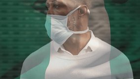 Animation of flag of nigeria waving over african american man wearing face mask in city street. global health precautions during covid 19 pandemic concept digitally generated video.