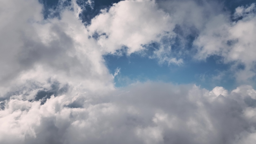 Aerial view Flying over clouds timelapse with daytime sun. Flying through moving clouds with beautiful highlights. Air travel. Ideal for cinema, background