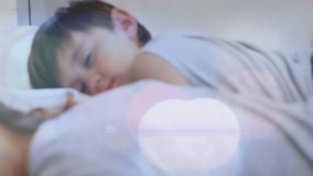 Animation of light spots over caucasian mother and son sleeping. Lifestyle and family concept digitally generated video.