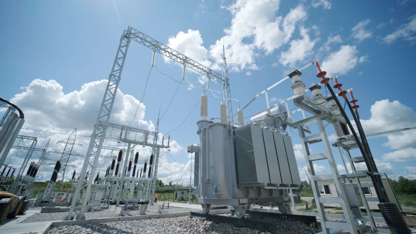 High voltage transformer against the blue sky. Electric current redistribution substation Royalty-Free Stock Footage #1094200185