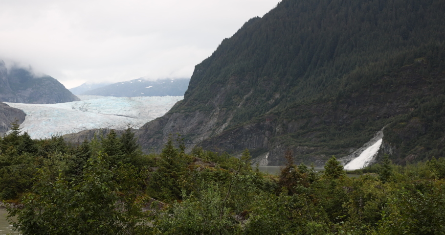 Mendenhall Glacier Nugget Falls forest Juneau Alaska. Cruise ship destination near Juneau Alaska. Climate change global warming result is rapidly retreating, shrinking, and melting. Large lake formed. Royalty-Free Stock Footage #1094205923