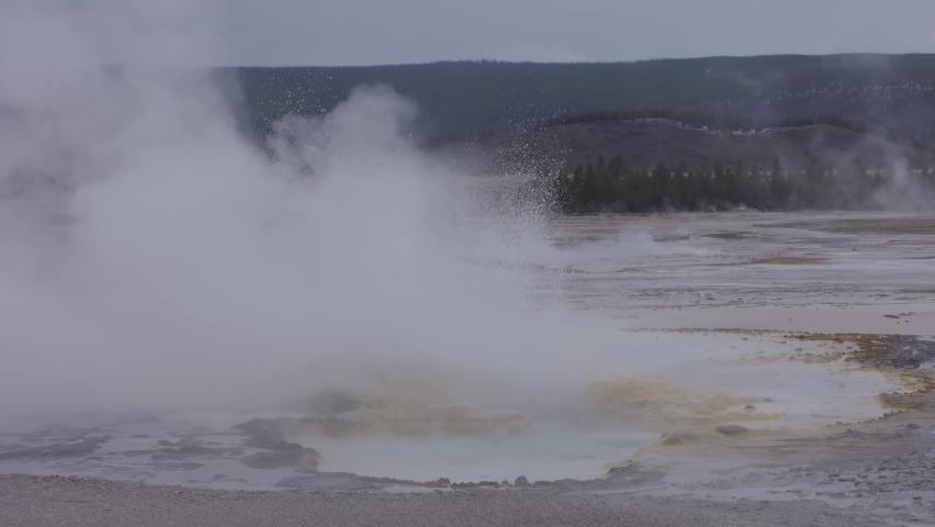 Hot spring Geyser with colorful water in American Landscape. Cloudy Sky. Yellowstone National Park, Wyoming, United States. Nature Background. Slow Motion