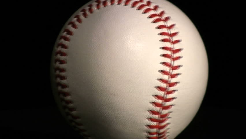 A baseball spinning over a black background