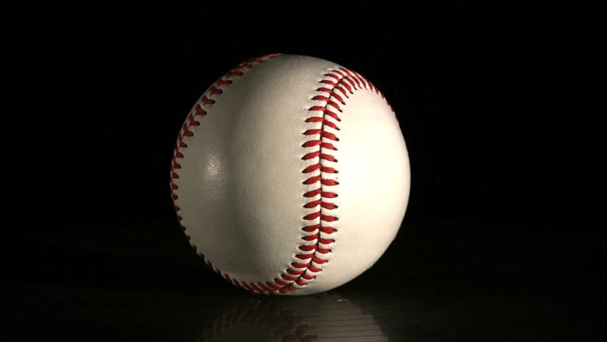 A baseball spinning over a black background
