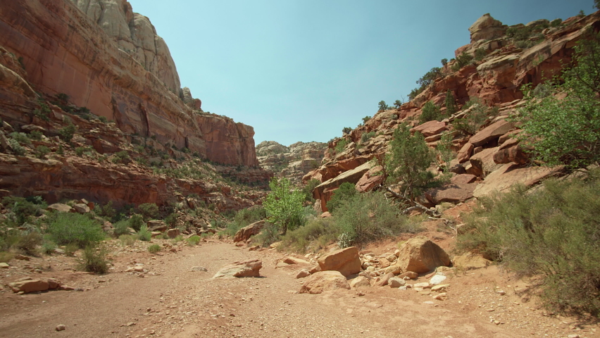 Scenic canyon trail with hiker walking between desert walls at Capitol Reef National Park, Utah. Move in.