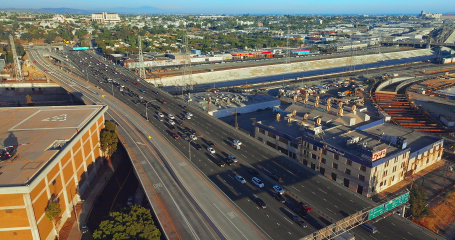 Los Angeles, USA - August 2022: Sunny panorama of green Los Angeles. Drone rising above the busy traffic road with numerous cars. Top view.
