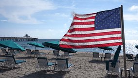 American flag flutters in the breeze with lounge chairs and the Deerfield Beach, Florida International Fishing Pier in the background in a sunny morning - Powered by Shutterstock - Get 15% off with code: PIKWIZARD15