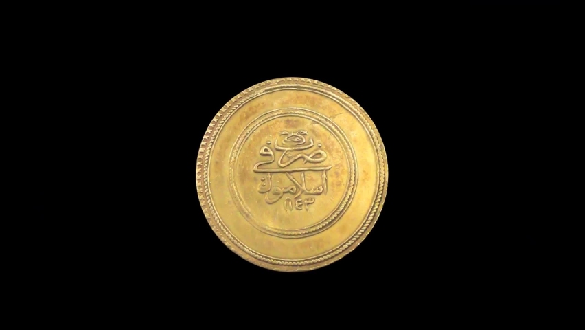 Rotating reverse of Ottoman coin 3 altin 1730 with inscription meaning MINTED IN ISTANBUL, isolated in black background. 