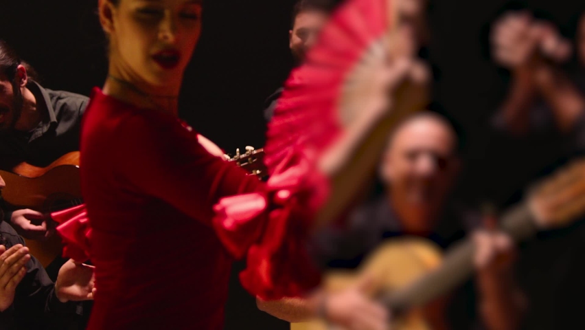 Beautiful stylish female artist dancing spanish style dance . Group of men playing on guitar and applauds to the dancer woman . Concept footage of spanish traditional culture . Waving cloth of skirt  | Shutterstock HD Video #1094229289