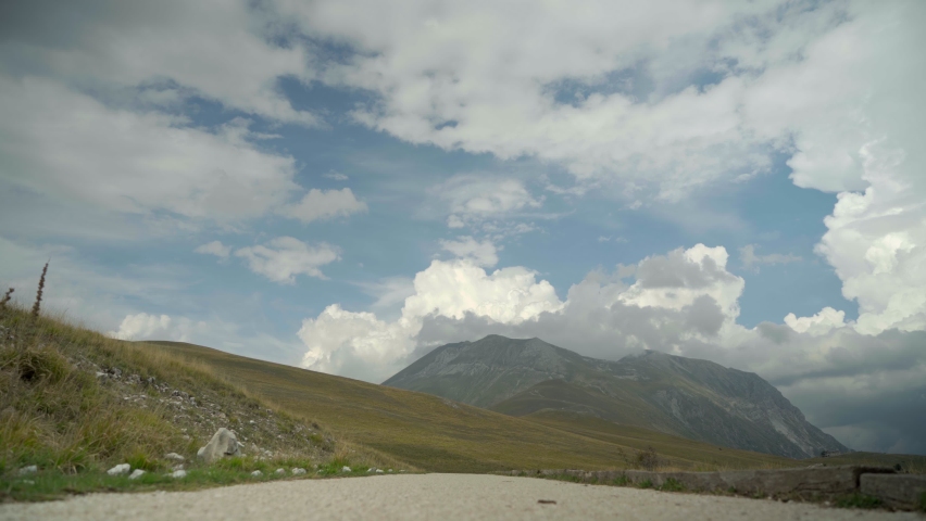 Two People Walking In A Valley Towards The Mountain