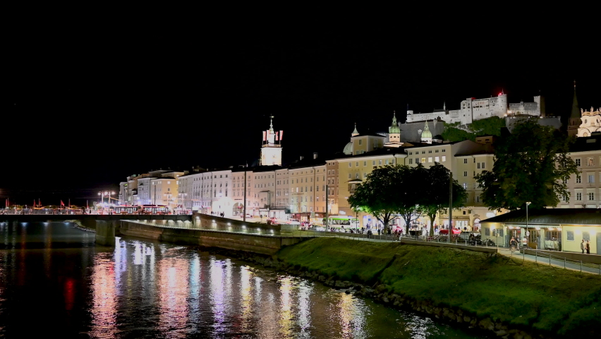 Salzburg, Austria, August 2022. Fascinating night shot of the old town. A lightning bolt lights up the sky blue in the third second of the footage. The fort at the top of the hill stands out