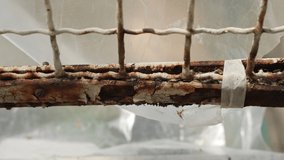 Heavy rusted metal surface of an old balcony, worker using handheld metal brush for corrosion and old paint removal. Steel brush rubbing surface and forming rusty dust in air, corroded surface - Powered by Shutterstock - Get 15% off with code: PIKWIZARD15