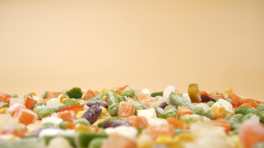 Falling frozen vegetables assorted, flying food on beige background. High quality FullHD footage | Shutterstock HD Video #1094244691