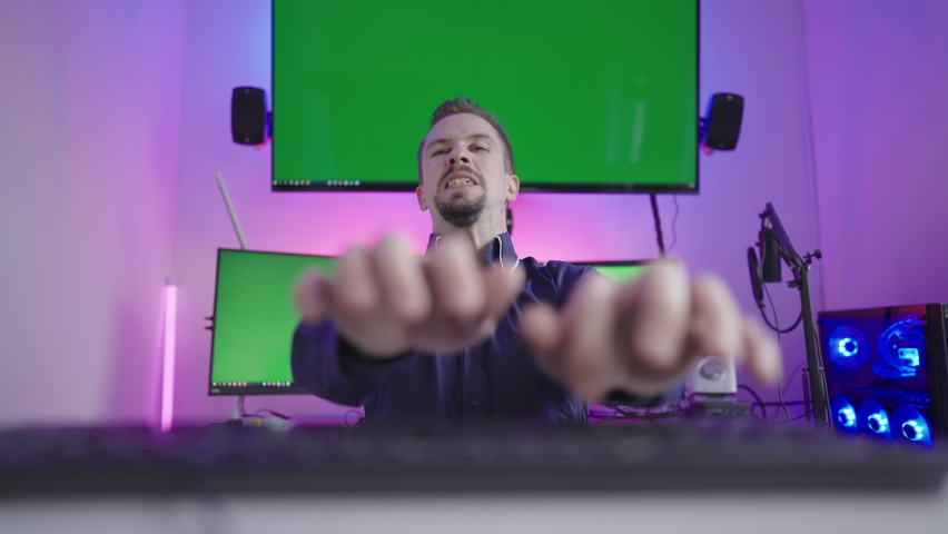 Online troll rage trashing on keyboard with green screens in background 4K Royalty-Free Stock Footage #1094248487