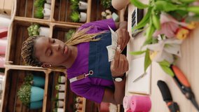 African american woman florist counting dollars vertical video at florist